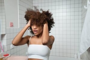 Young woman with curly hair in bathroom starting her morning self-care routine.